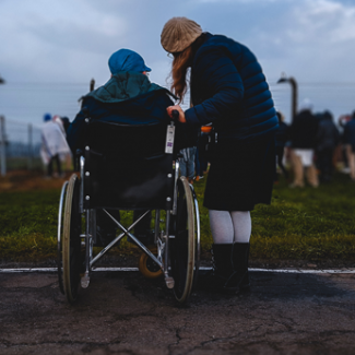 Wheelchair user and carer in a field of people
